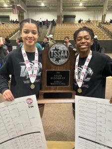 Mariana Bowen and Jes Barefield show their first-place medals and brackets after winning championships.